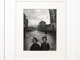 black and white photograph of two people standing on a cobblestone street