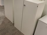 three white cabinets in the corner of a room
