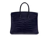 a black crocodile skin handbag on a white background