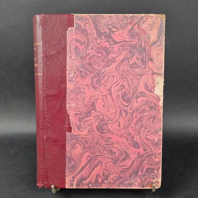 an old book with a red cover sitting on top of a black surface