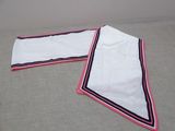 pair of white towels with red and blue trims on a bed