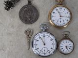 three different types of pocket watches and a coin