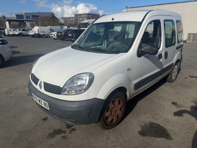 La petite camionnette blanche est garée sur un parking, à côté d'autres voitures.