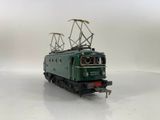 a green train that is on the tracks on a white surface