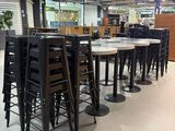 Des tables et des chaises sont alignées dans une grande pièce dotée de nombreuses fenêtres.