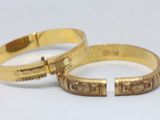 deux bracelets rigides en or ornés de motifs gravés sur un fond blanc