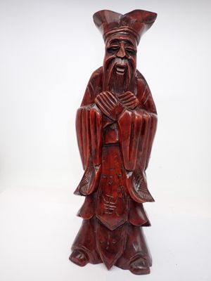 une vieille statue en bois représentant un homme barbu coiffé d'un chapeau
