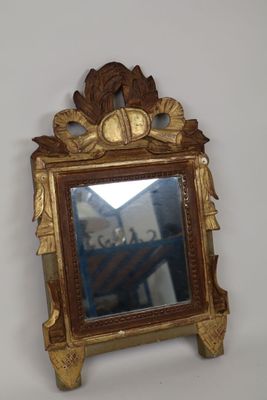 un miroir avec un cadre doré sur un mur blanc