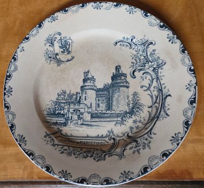 une assiette bleue et blanche sur laquelle est représenté un château