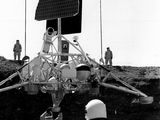 photographie en noir et blanc d'un homme debout devant un rover spatial