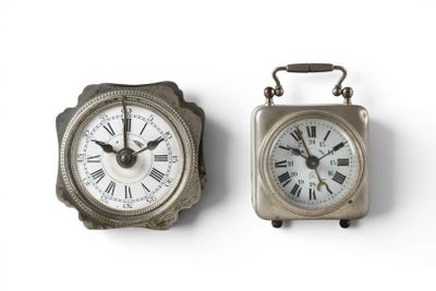 two clocks sitting side by side on a white surface