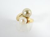 une image représentant une bague en or et perles posée sur une surface blanche