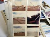 a pile of pictures on a table with a person holding a cell phone