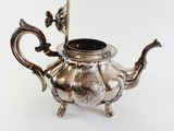 an antique silver teapot with a handle on a white background