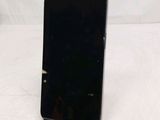 a black cell phone sitting on a stand on a white surface