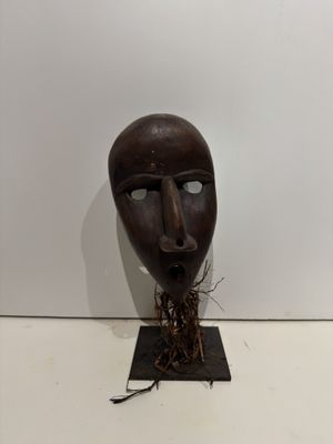 an old wooden mask with a plant growing out of it ' s mouth