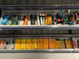 many pens and pencils in the bins on the shelf