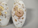 two white vases with gold designs on them