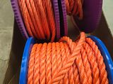 une corde orange dans une boîte, surmontée de bobines violettes