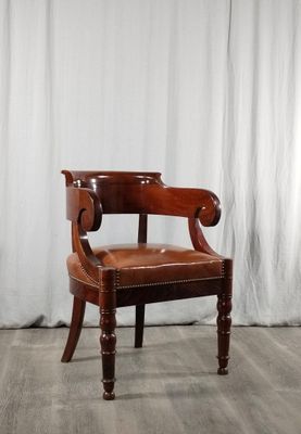 une chaise en bois avec une assise en cuir marron, posée sur un parquet