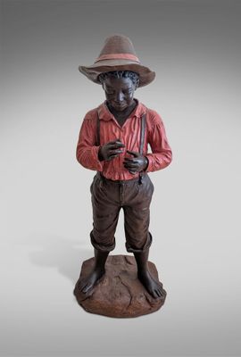 statue of a man with a hat and a red shirt standing on a rock