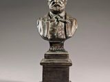 a bronze bust of a man with a bow tie on a pedestal