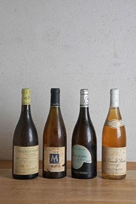 des bouteilles de vin alignées sur une table en bois, avec un mur en arrière-plan