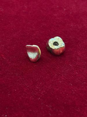 un gros plan sur une paire de perles métalliques posées sur une surface rouge