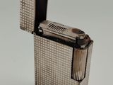 un vieux briquet en argent posé sur une surface blanche