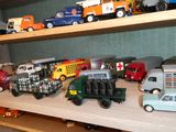 de nombreux camions miniatures posés sur une étagère dans une pièce