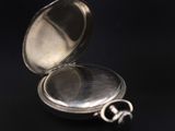 a silver pocket watch sitting on a black surface