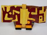 une sculpture rouge et jaune sur une surface blanche