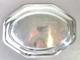 a silver plate on a table that has a reflection of a person in it