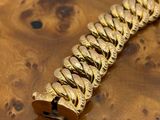 a close up of a gold bracelet on a wooden table