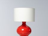 une lampe de table rouge avec un abat-jour blanc, posée sur une table blanche