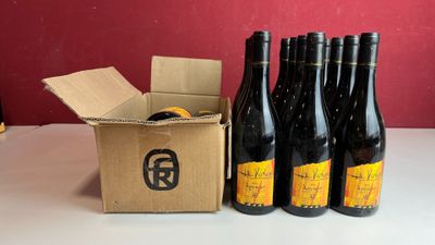 six bouteilles de vin sont posées dans un carton, à côté d'un autre carton
