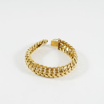 gros plan d'un bracelet en or sur fond blanc