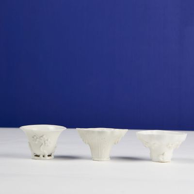 three white bowls sitting on top of a white table next to a blue wall