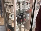 a man standing in front of a display case filled with bottles
