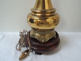 a gold lamp that is on a wooden stand