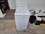 une machine à laver blanche posée à côté d'une poubelle noire