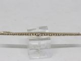 a close up of a gold and diamond bracelet on a clear stand