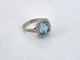 a close up of a ring with a blue topaz stone surrounded by diamonds