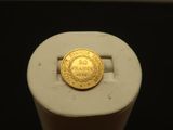 une pièce d'or posée sur un socle blanc