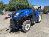 un tracteur bleu garé sur un parking en gravier