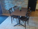 a table with chairs and a vase of flowers on it