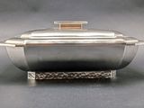 a silver bowl with a lid sitting on a stand