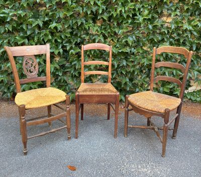trois chaises en bois placées les unes à côté des autres devant une haie