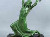 une statue verte représentant une femme tenant une fleur, posée sur un socle en marbre
