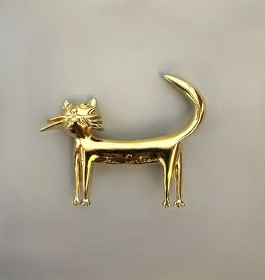 a gold cat brooch with a flower in it ' s mouth